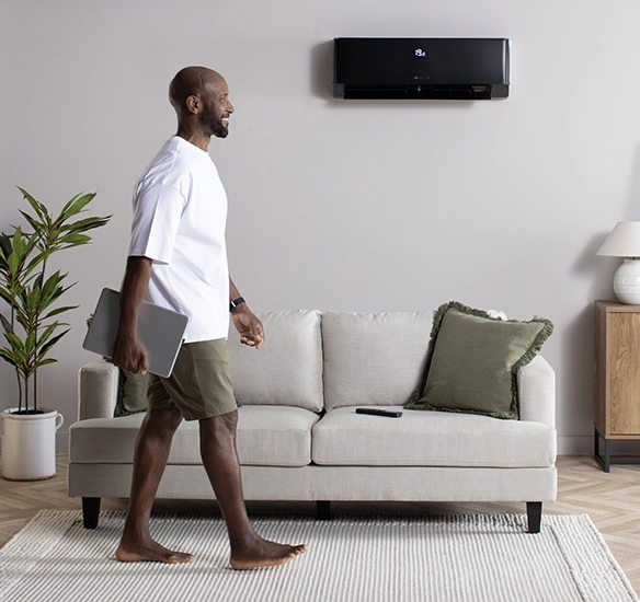 man walking with laptop past air con